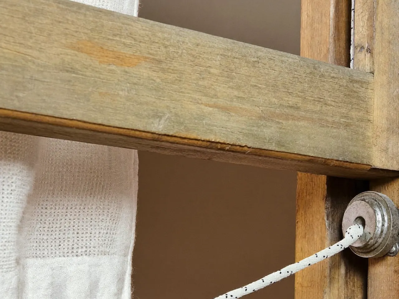 Detail of a brass pulley wheel in a sash window frame